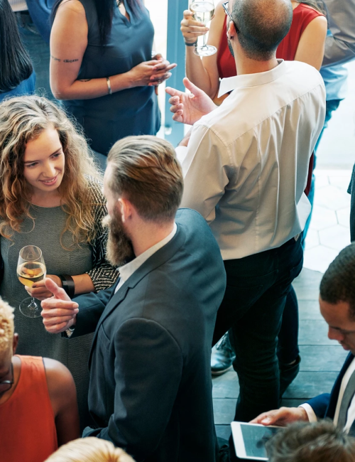 A social mixer with diverse professionals mingling, chatting, and sipping drinks at a bright, crowded networking event. Top it at 140 characters, always ending the sentence.