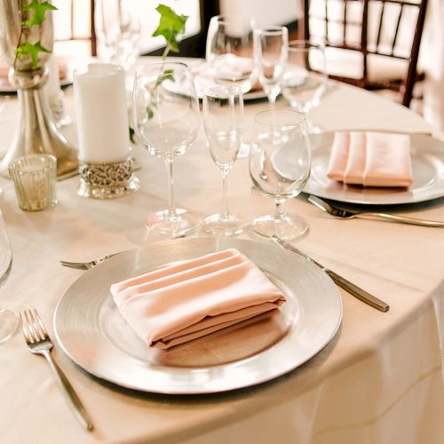 A formal dining setup with a white tablecloth, elegant place settings, folded napkins, multiple glasses, candles, and polished cutlery, ready for a meal.