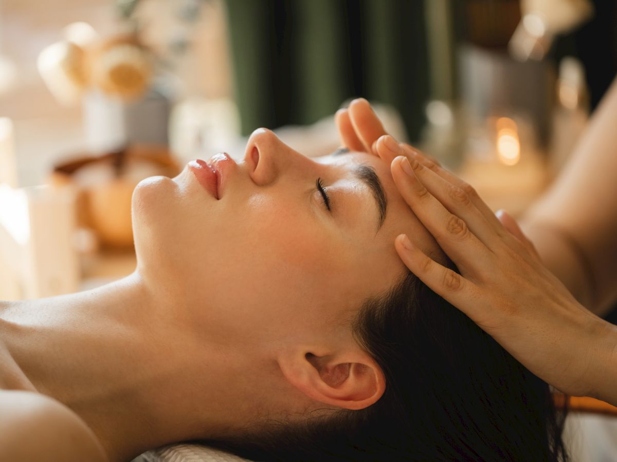 A spa massage: a therapist gently kneads a client&rsquo;s face and neck with relaxing touch.