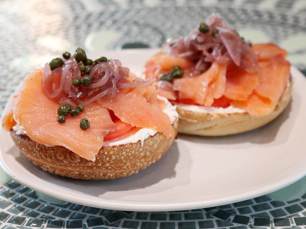 Two toasted bagel bites topped with cream cheese, smoked salmon, pickled onions, capers&mdash;delicious appetizer on a plate.