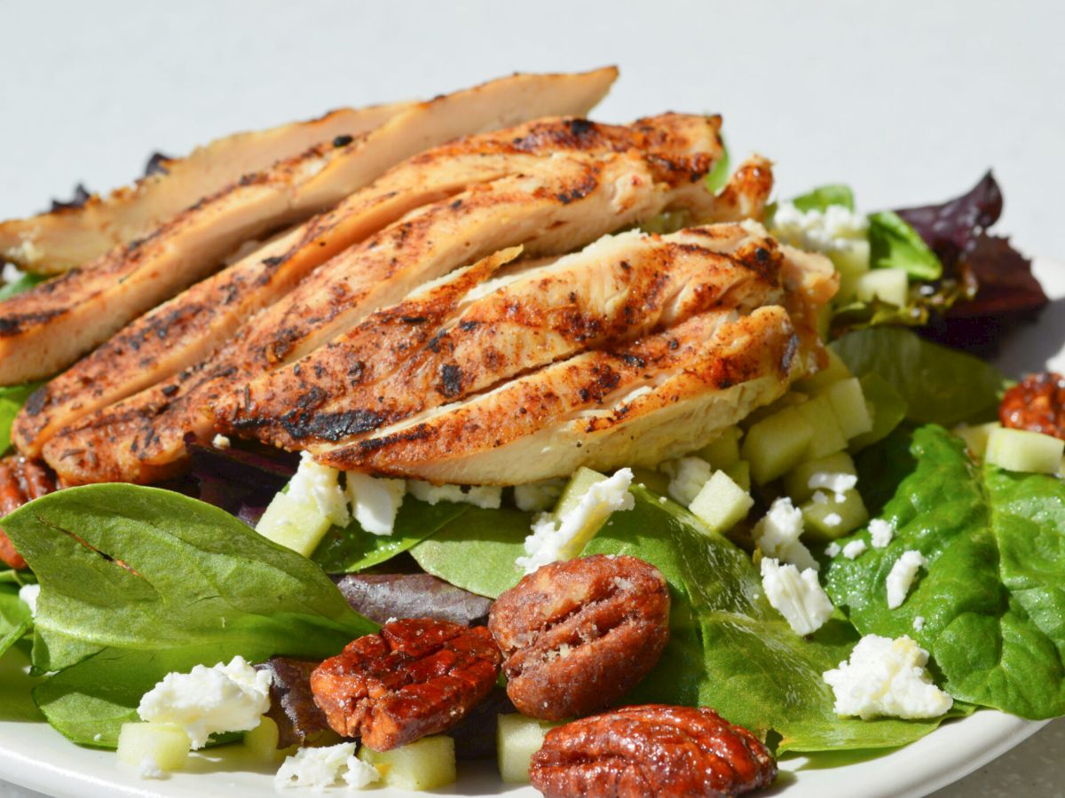 Grilled chicken slices atop a mixed greens salad with feta, almonds, apples/pears, and a light vinaigrette&mdash;colorful, healthy, and flavorful.